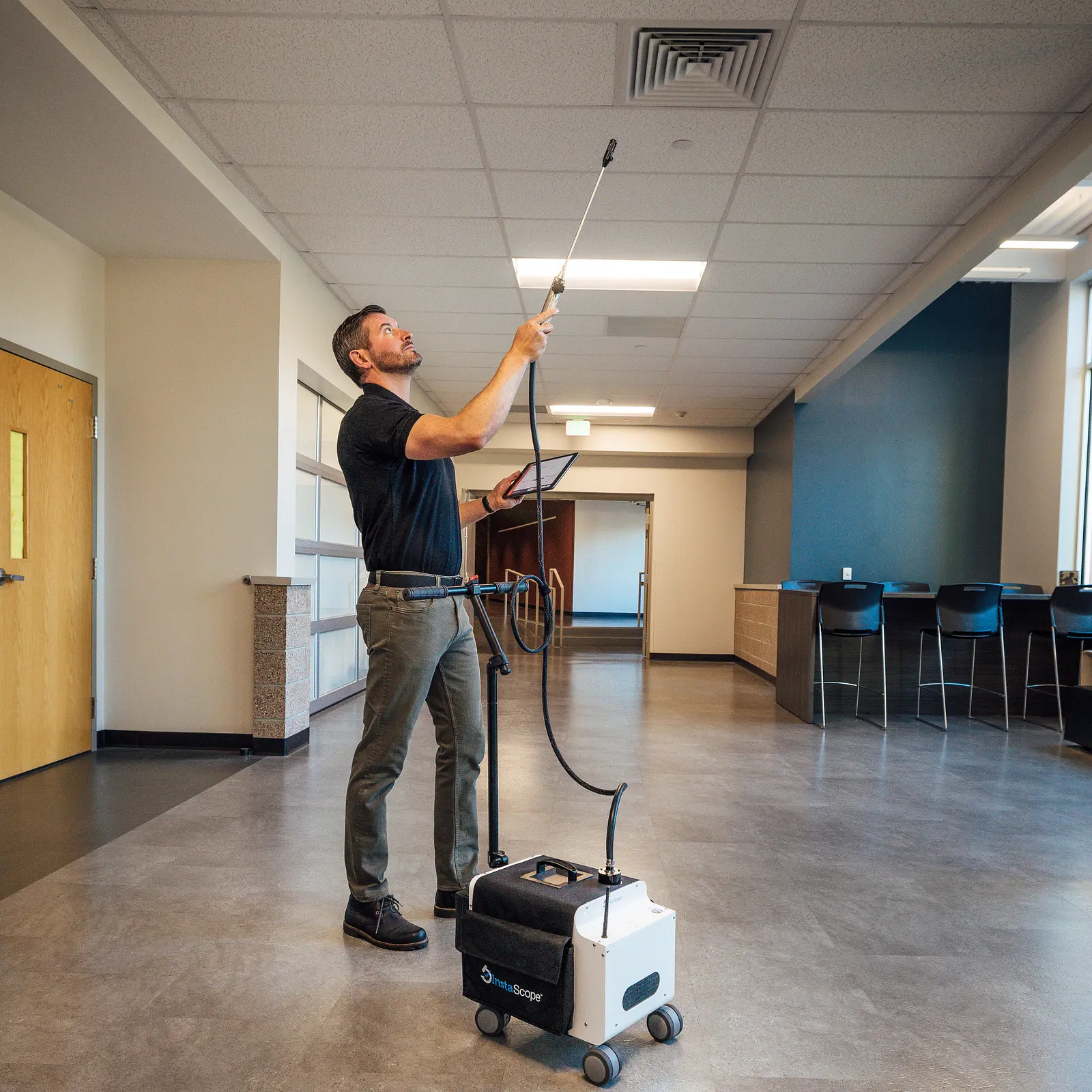 Spore Scan technician using InstaScope equipment at a ceiling vent